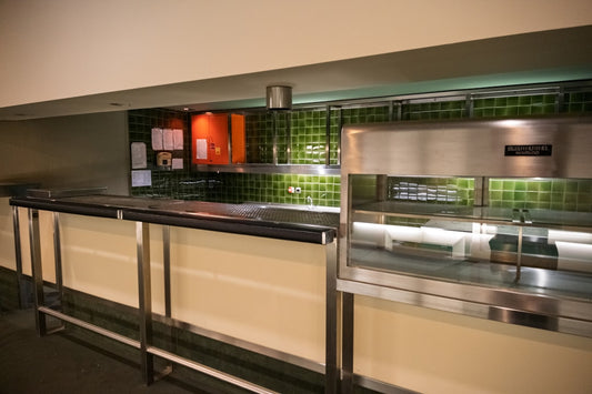 A modern cafeteria serving counter with stainless steel equipment.